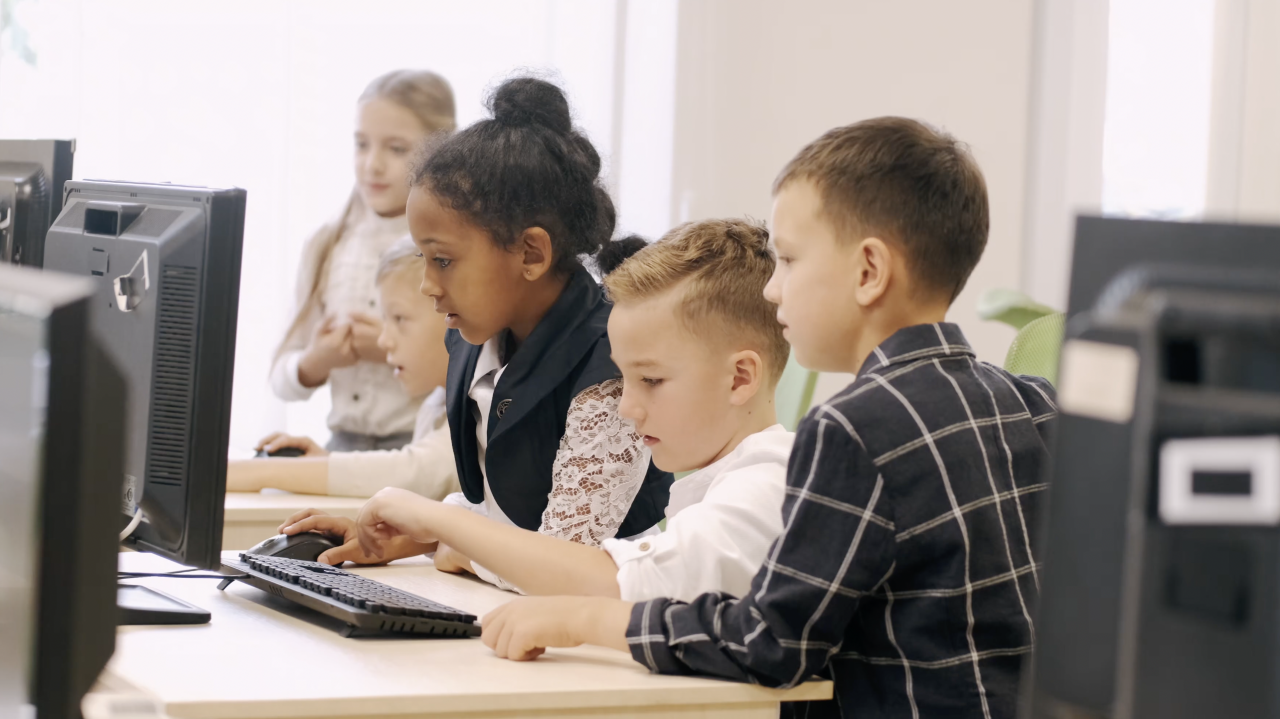 Four school children in a classroom looking at a computer