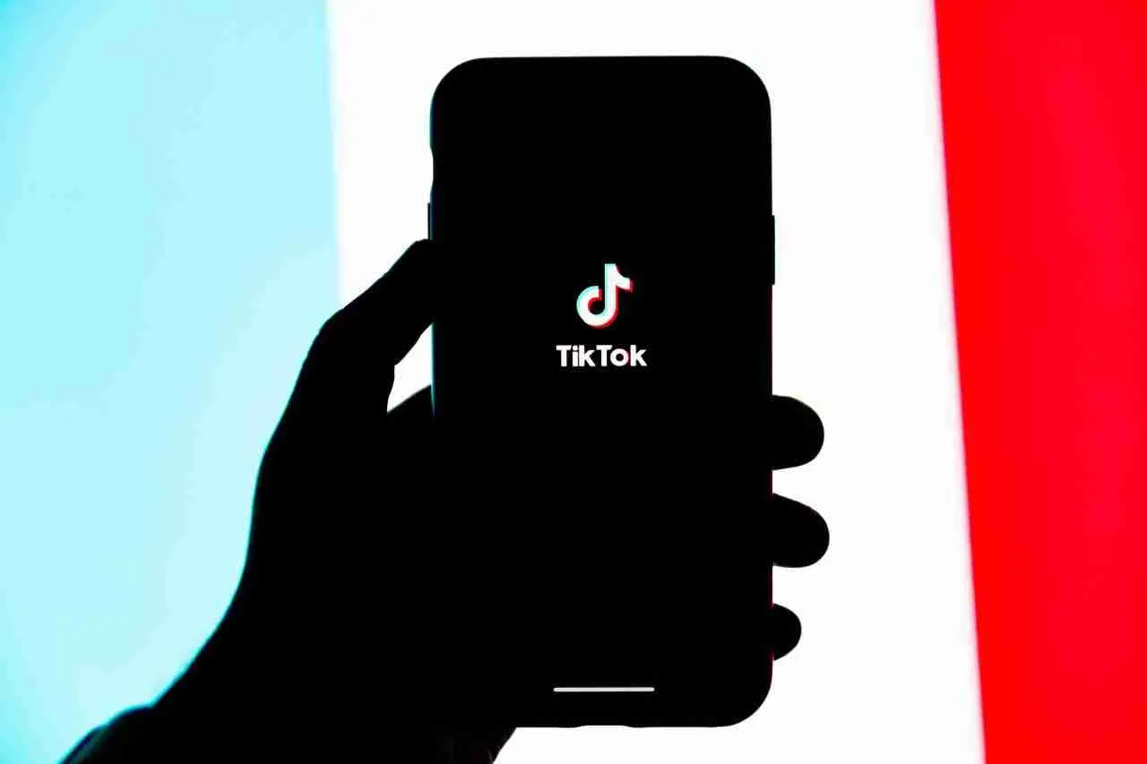 Andrew Tate: Someone holding a phone showing a TikTok logo