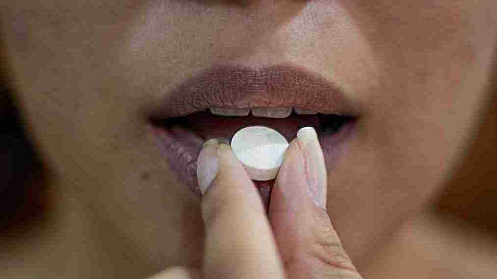 woman putting a pill on her lips