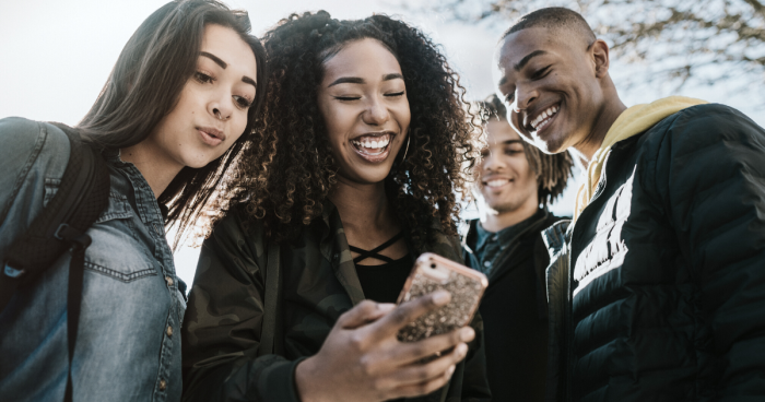 Group of people looking at a phone and smiling
